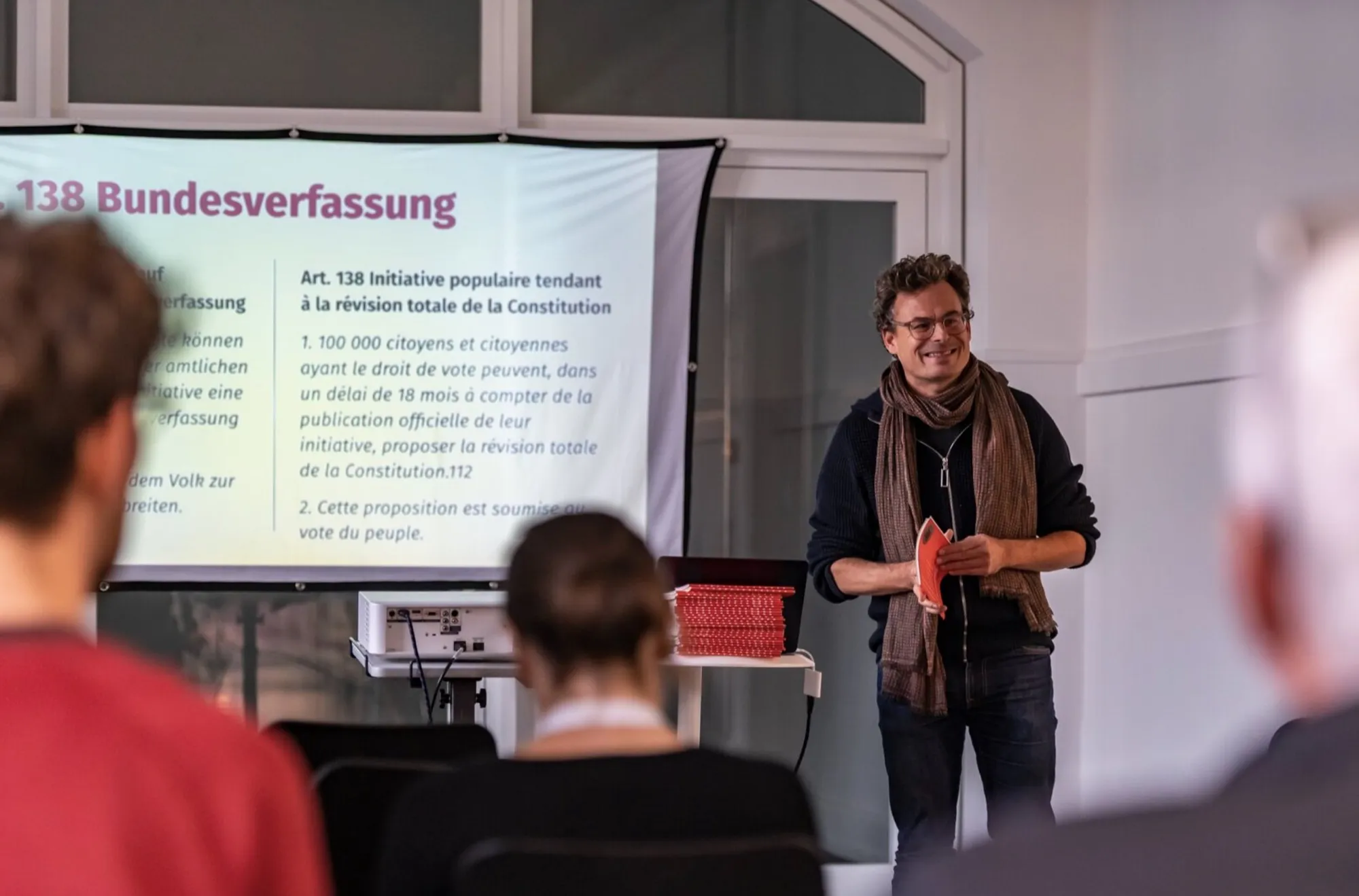 Daniel Graf spricht vor einer Leinwand mit Artikel 138 der Bundesverfassung