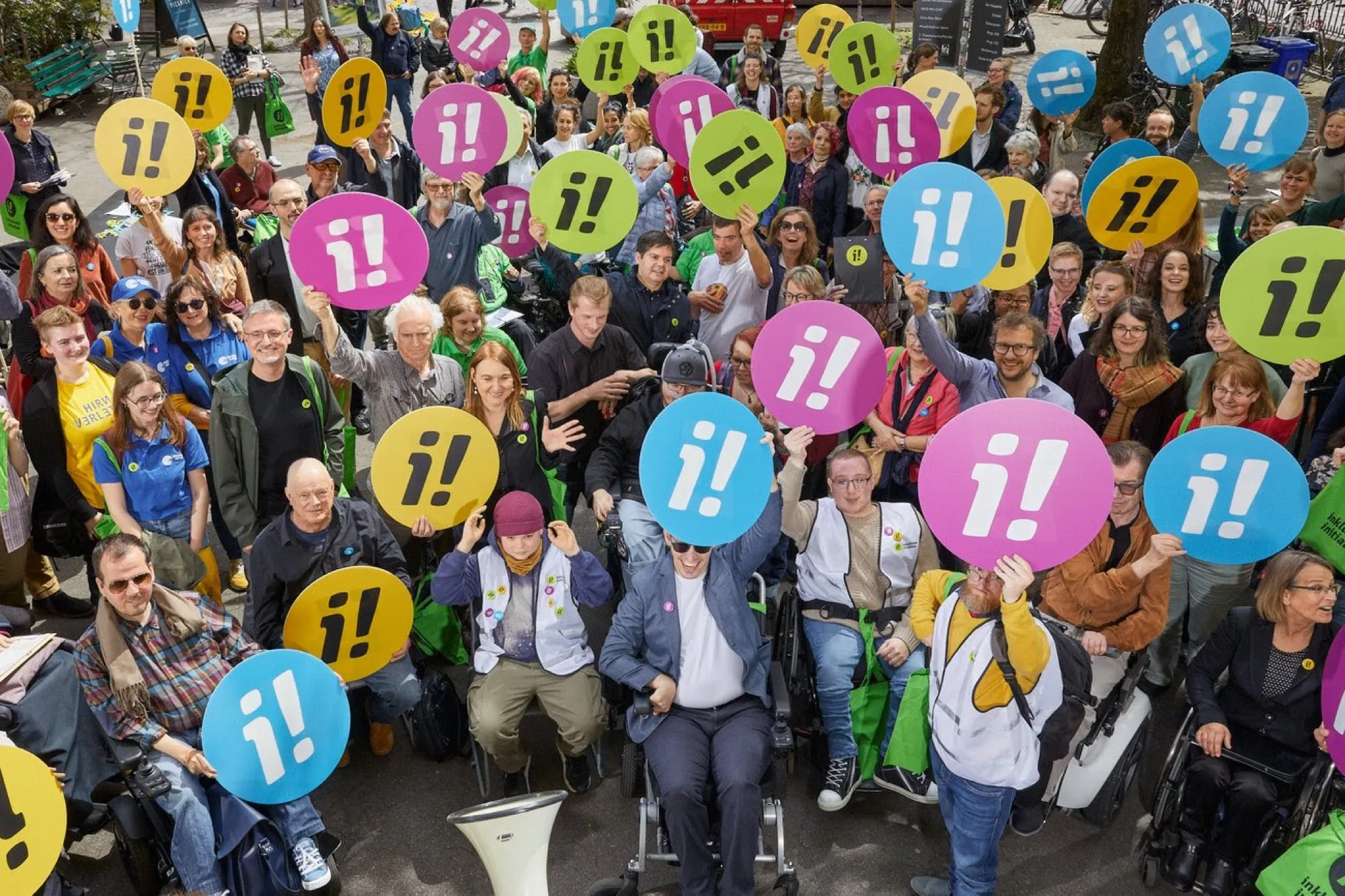 Gruppenbild von oben: viele Unterstützer:innen der Inklusions-Initiative mit bunten runden Schildern