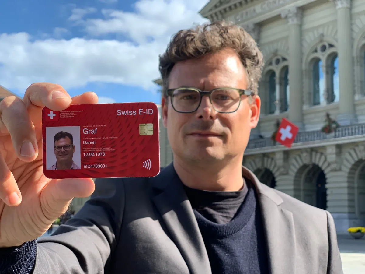 Daniel Graf hält vor dem Bundeshaus eine Muster-Karte «Swiss E-ID» mit seinem Foto